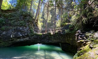 Beautiful natural pond in a forested area with clear green water, sunlight filtering through the trees. | © Kleinwalsertal Tourismus eGen 