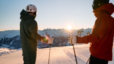 Zwei Skifahrer beim Skilauf auf Schneepisten in den Bergen bei Sonnenaufgang oder Sonnenuntergang. | © Kleinwalsertal Tourismus eGen • Fotograf: Oliver Farys